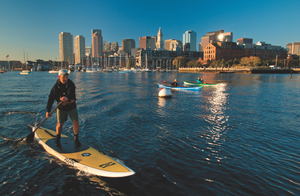man stand up paddleboarding on the charles river, massachusetts