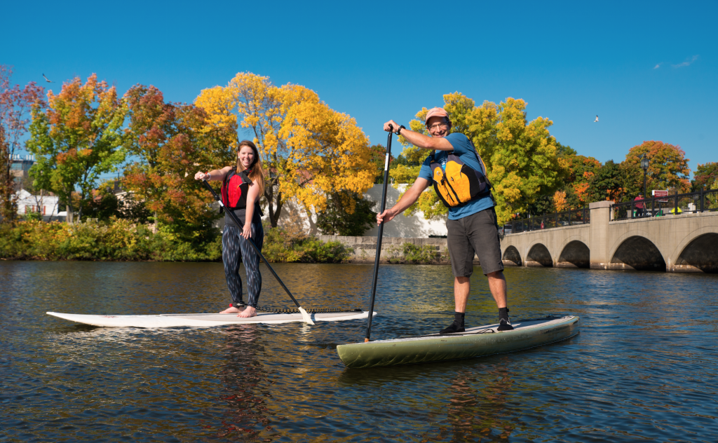 mand and woman stand up paddleboarding on the Charles