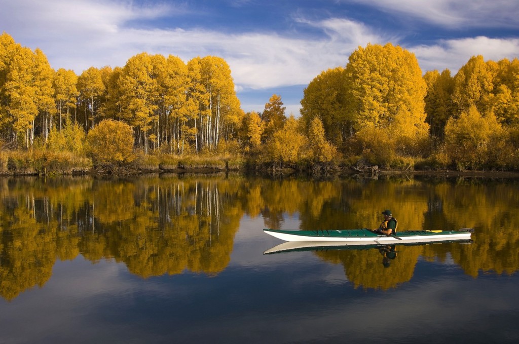 man kayaking on lake with trees in background