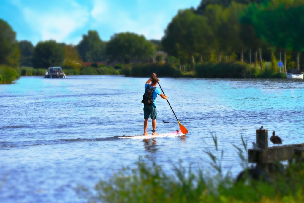 man stand up paddleboarding on a river