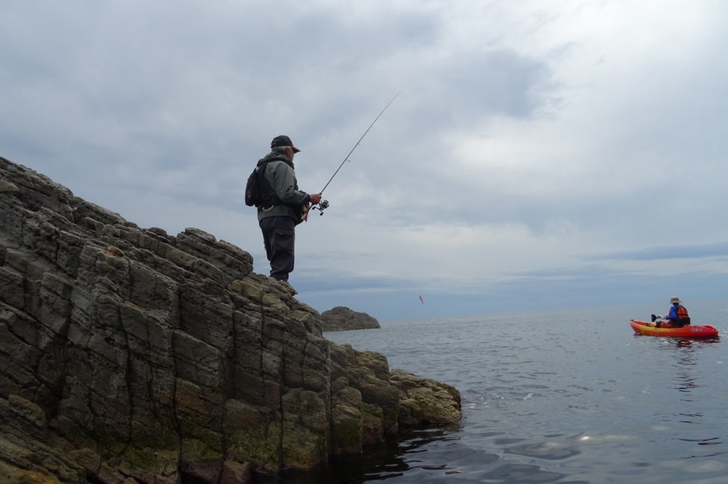 fisherman standing on rock with sea in background