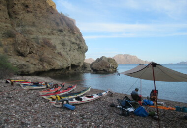Sea kayaks and a beach umbrella along the coast near Loreto, Baja Sur, Mexico